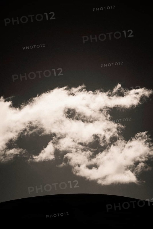 Fluffy clouds float gracefully across a darkening sky, illuminated softly by fading daylight, creating a serene and captivating atmosphere at twilight