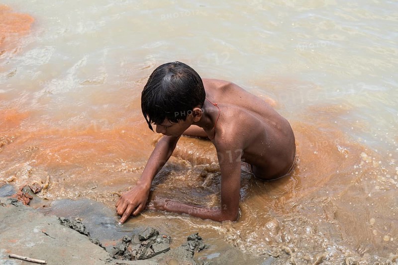 A boy sits in the bank of Brahmaputra River as he bathe to seek relief from the intense summer heat in Guwahati, India, on June 26, 2025