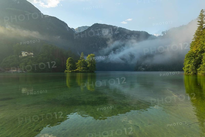 Mystical morning at Königssee in Schönau with boathouses and Christlieger. Sunrise and beautiful wafts of mist over the Königssee in the basin