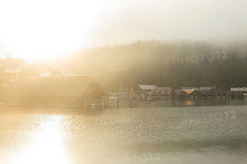 Mystical morning at Königssee in Schönau with boathouses. Sunrise and beautiful wafts of mist over the Königssee in the basin