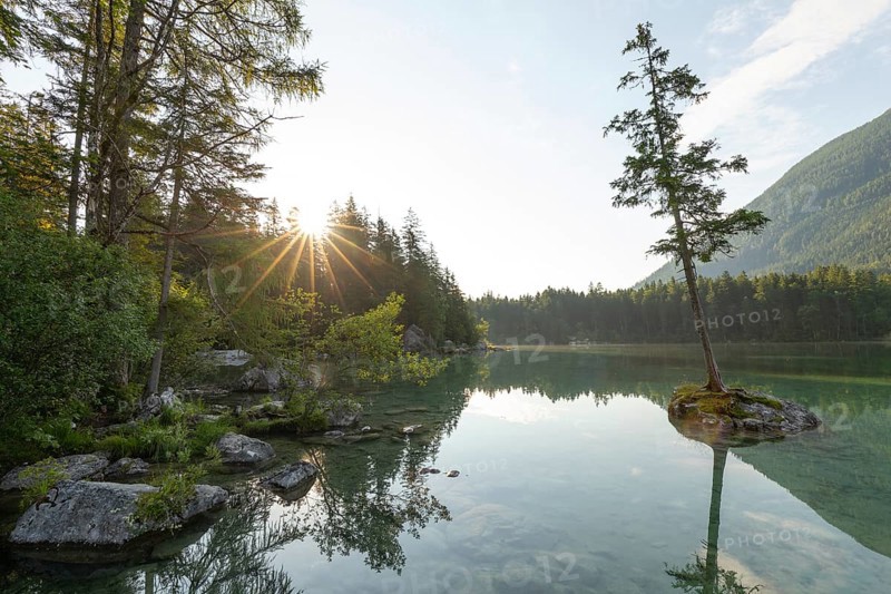 Summer morning at Hintersee near Ramsau in Berchtesgadener Land with sun star and reflection