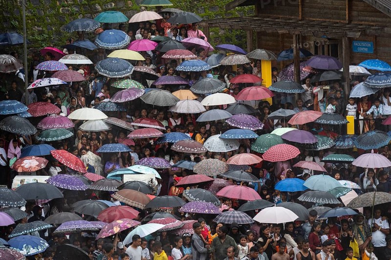 People attend holding umbrellas at an event organised to mark the Behdienkhlam festival in Jowai, India on July 14, 2025. Behdienkhlam is a vibrant annual festival celebrated by the Pnar (Jaintia) community of Meghalaya, especially in Jowai, to drive away plague and diseases and to pray for a good harvest. Observed in July after the sowing season, it features traditional rituals, offerings to ancestral spirits, and the grand procession of beautifully decorated bamboo structures called rots, which are later immersed in a sacred muddy pool known as Ka Aitnar