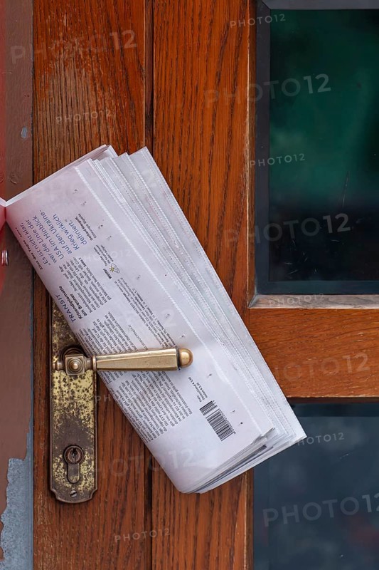 Fresh newspaper waiting at the door in the early morning. Newspaper on the door handle