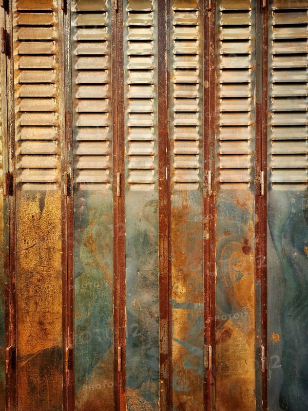Rustic wooden shutters exhibit a blend of rusty and faded paint, showcasing years of weathering in an urban setting illuminated by natural light, offering a glimpse into its history