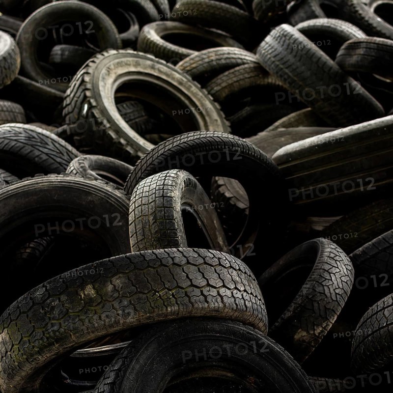 A large collection of worn-out tires is stacked chaotically in a junkyard, illustrating the environmental concerns of tire disposal and recycling efforts. France