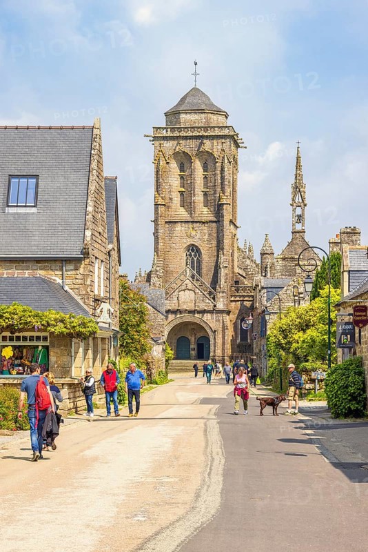 Tourists on city street in the old town of Locronan with the church a sunny summer day, Locronan, Bretagne, France