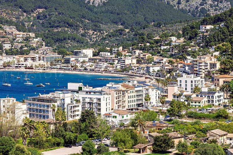 View at a tourist resort by a sea bay by the mountains with houses by the beach a sunny summer day, Port de Sóller, Mallorca, Spain