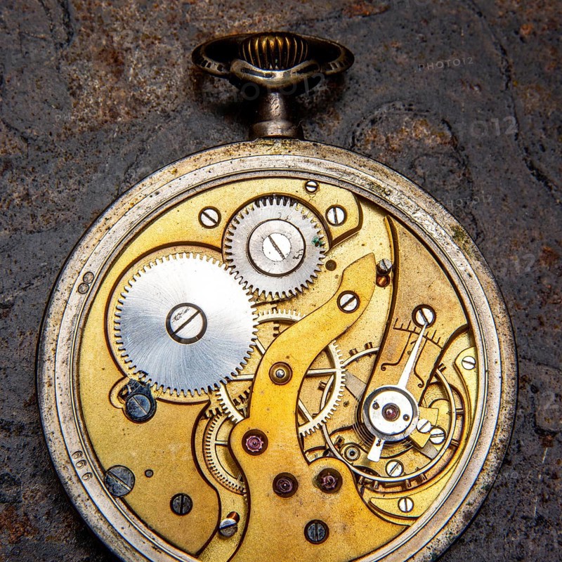 A detailed close up of a vintage pocket watch reveals its delicate gears and mechanisms. This exquisite craftsmanship highlights the artistry involved in timekeeping