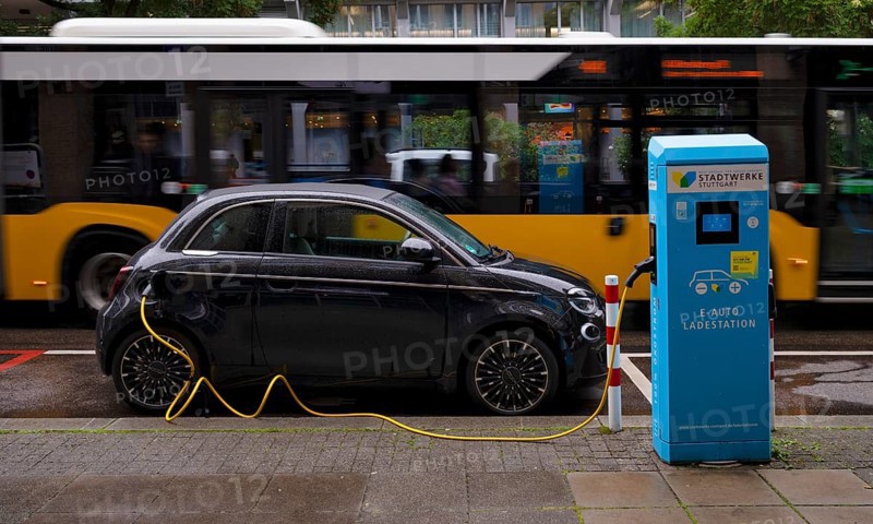 Charging station Stadtwerke Stuttgart for electric cars, charging station, e-charging station, e-mobility, charging cable leads into e-car, logo, behind it drives yellow bus, public transport, local transport, SSB, city bus, movement effect, Stuttgart, Baden-Württemberg, Germany
