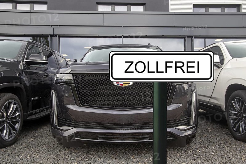 (Photomontage) Symbolic image of the customs agreement between the EU and the USA: sign with the inscription ZOLLFREI in front of a new Cadillac at the dealership