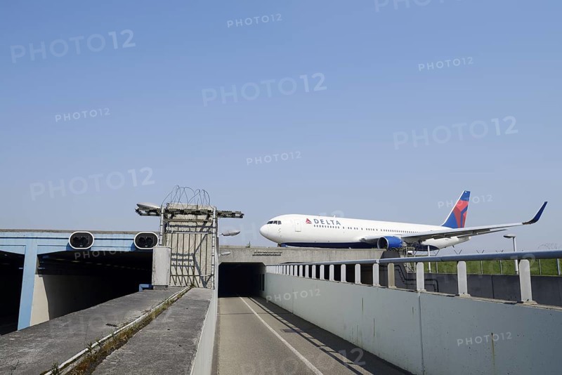 Aeroplane taxiing over a bridge over a road and cycle path, Amsterdam-Schiphol Airport, North Holland, Netherlands
