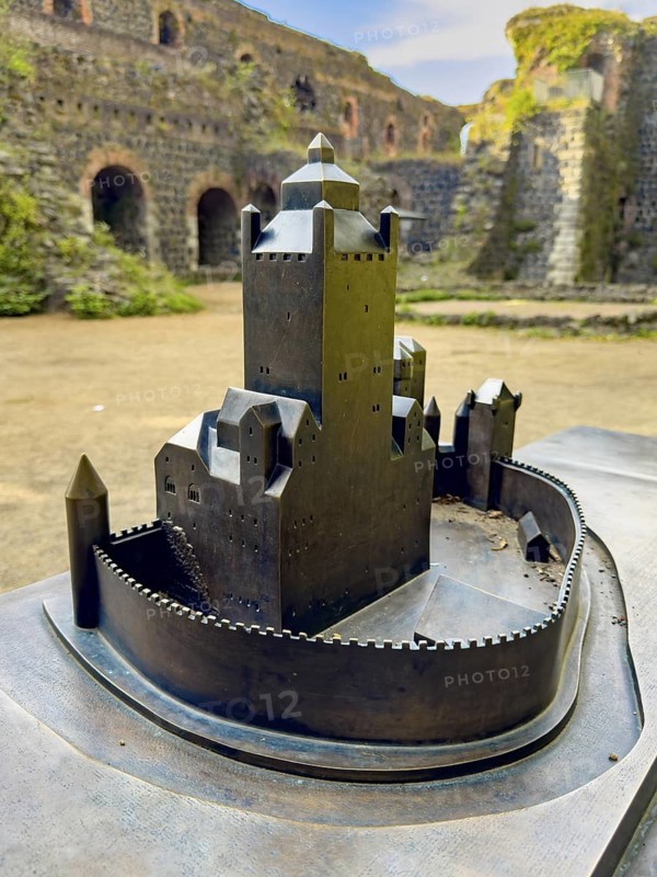 Small metal model of the original fortress building Schloss Burg of the imperial palace of Emperor Frederick I Barbarossa, built in the Middle Ages around 1184 on today's banks of the Rhine, in the background ruins of it, Kaiserswerth, Düsseldorf, North Rhine-Westphalia, Germany