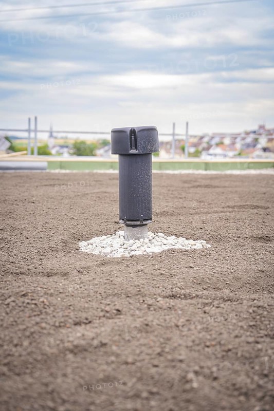 Single ventilation shaft on a green roof with city in the background, green roof, house construction, climate neutral