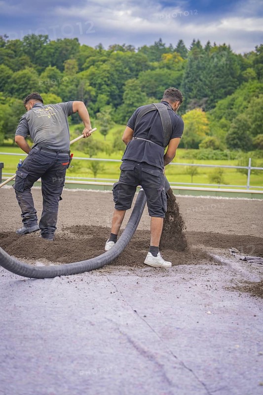 Two workers lay material with a hose on a roof on a green site, roof greening, house construction, climate neutral
