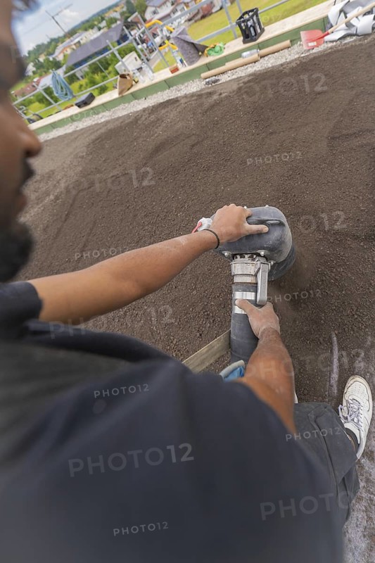 Close-up of a worker using a tool on a floor, roof greening, house construction, climate neutral