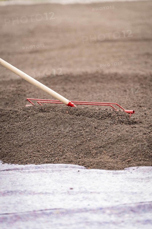 Close-up of a tool spreading soil on a construction site, roof greening, house construction, climate neutral