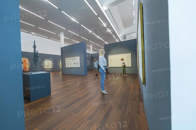 People looking at paintings in a modern art gallery with wooden floor and dark walls, Frieder Burda Museum, Baden Baden, Germany