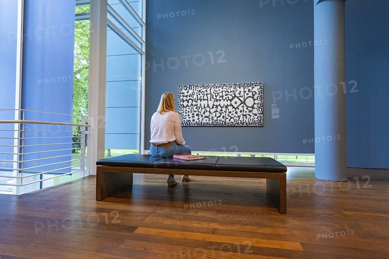 A woman sits on a bench in front of a modern work of art and looks at it attentively, Frieder Burda Museum, Baden Baden, Germany