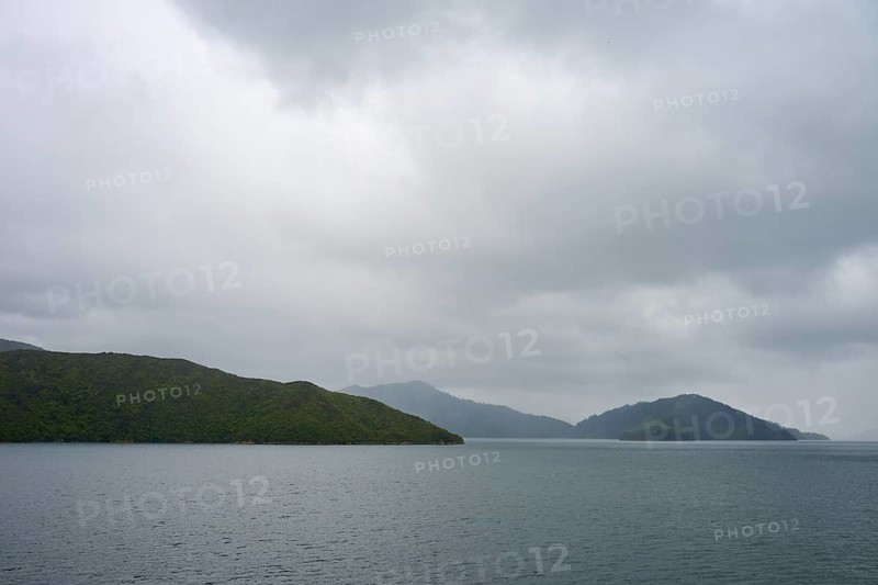 View of calm sea with cloudy sky and green islands, summer, Cook Strait, North Island, South Island, New Zealand