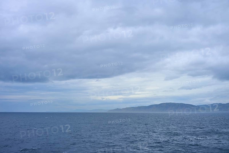 View of the sea and a distant coastline under a cloudy sky, summer, Cook Strait, North Island, South Island, New Zealand