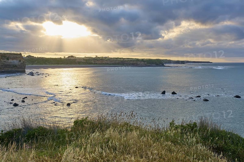 Waves on the coast under a dramatic sky, sunbeams breaking through the clouds, summer, Opunake, Taranaki, North Island, New Zealand