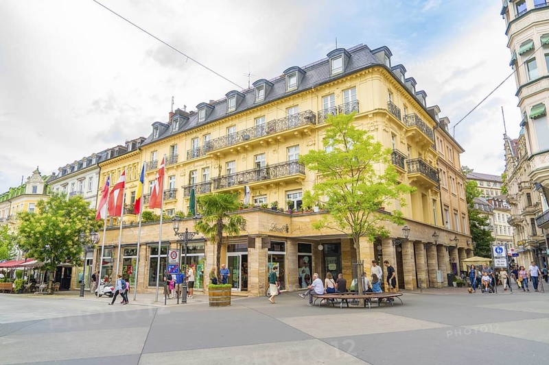 Corner building with balconies and flags, lively with people, urban atmosphere, Baden Baden, Germany