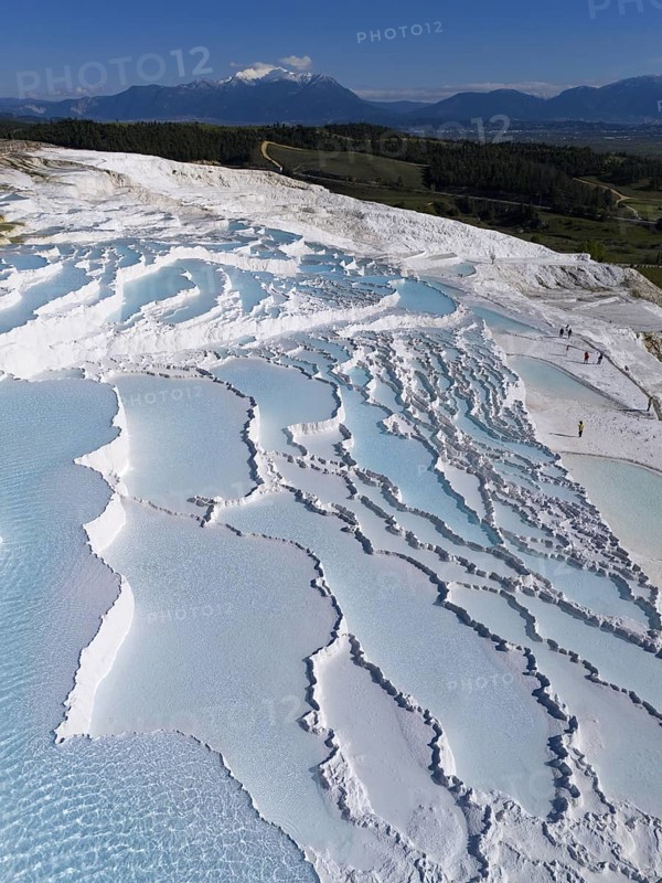 Terraces of turquoise water in white formations, mountains visible in the background under a clear sky, aerial view, sinter terraces, lime sinter terraces, travertine terraces, Pamukkale, Denizli, UNESCO World Heritage Site, Anatolia, Turkey