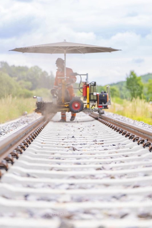Wide-angle shot of a welder on a railway track, surrounded by nature, grinding work on the Hermann Hesse railway, Ostelsheim, district of Calw, Germany