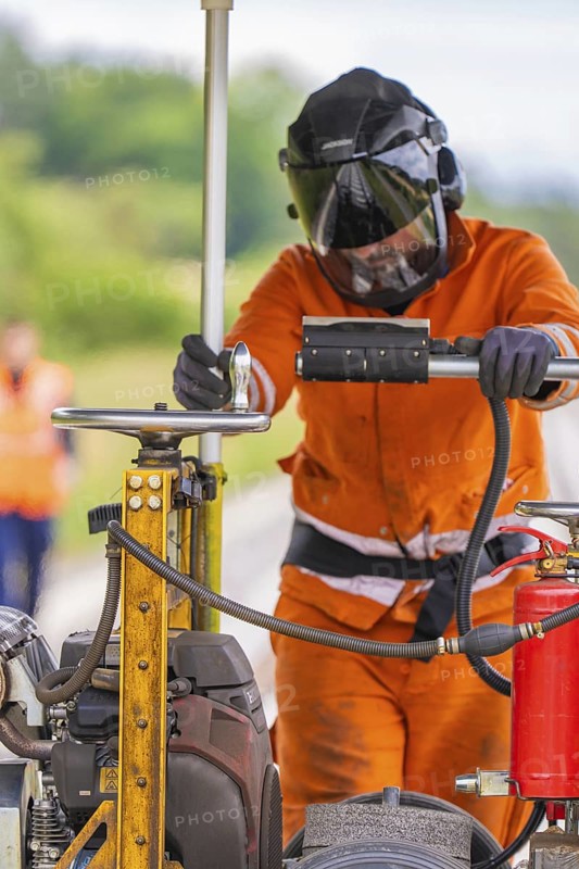 A worker in protective clothing works with heavy equipment on a railway track, grinding work on the Hermann Hesse railway, Ostelsheim, district of Calw, Germany