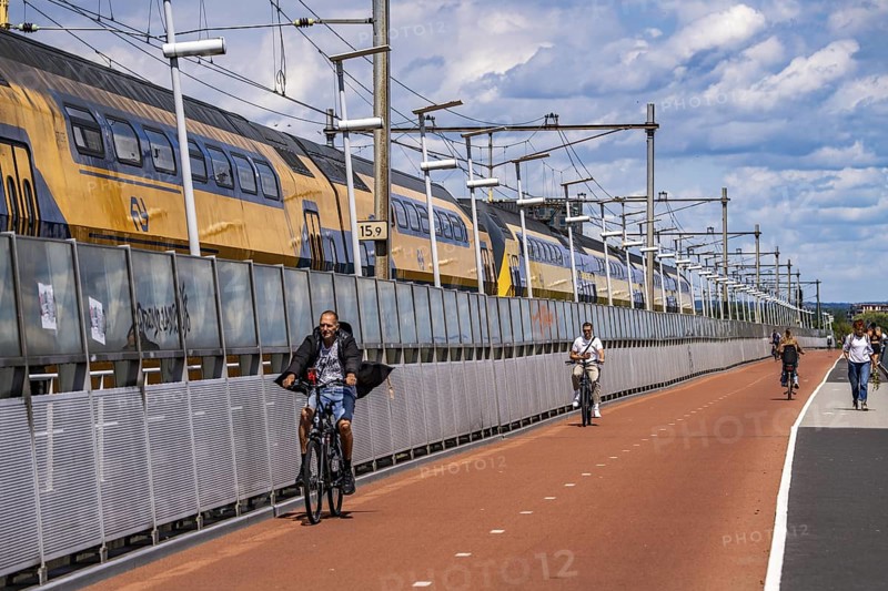 Cycle and pedestrian bridge Snelbinder Brug, over the river Waal near Nijmegen, was added to the existing railway bridge, fast cycle path connection from the city centre of Nijmegen and the new housing estates in the Waalsprong district, Netherlands