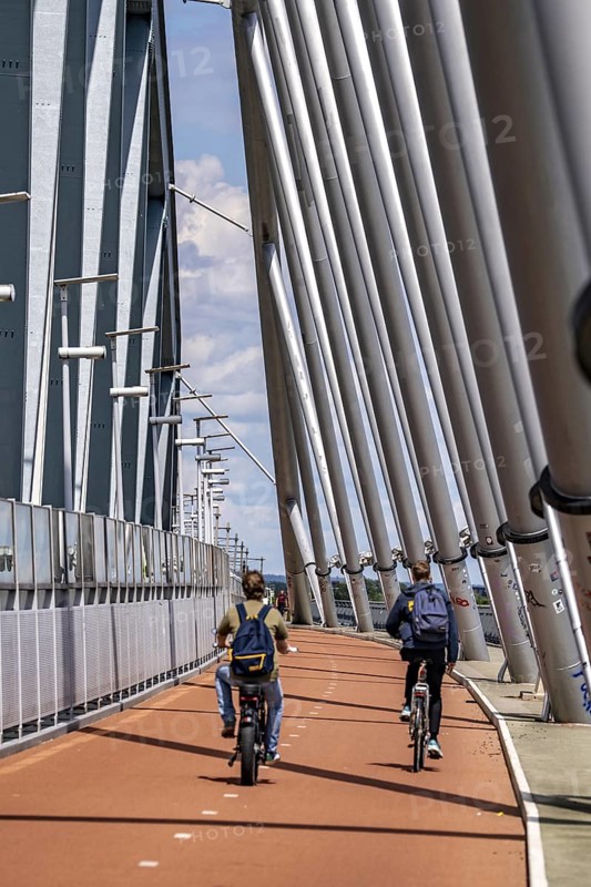 Cycle and pedestrian bridge Snelbinder Brug, over the river Waal near Nijmegen, was added to the existing railway bridge, fast cycle path connection from the city centre of Nijmegen and the new housing estates in the Waalsprong district, Netherlands