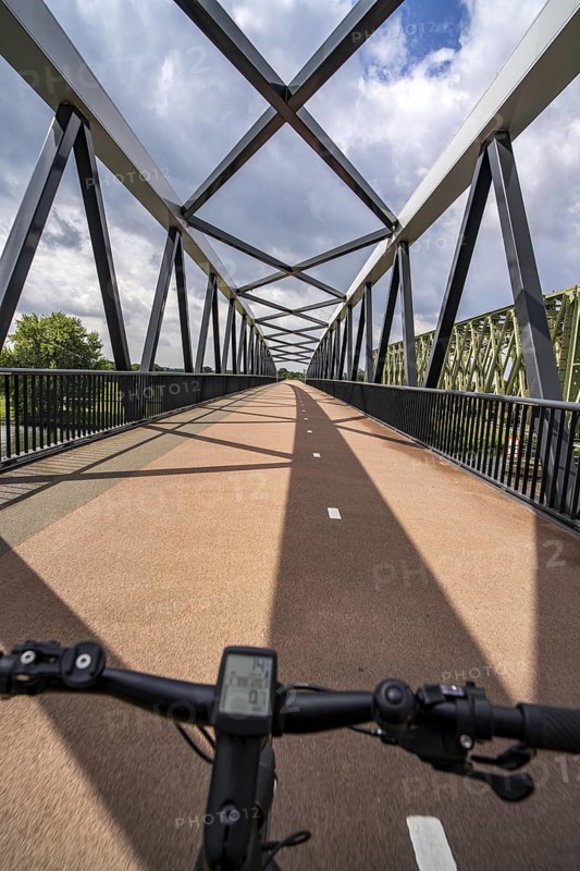 Ride over the De Massover cycle path bridge, over the Meuse south of Nijmegen, near Cuijk, part of the MaasWaalpad long-distance cycle path, 12 km between Nijmegen and Cuijk, built in 2021, for 15 million euros, Meuse river crossing for cyclists and pedestrians, part of a cycle path network, used by many commuters, next to a railway bridge, Netherlands