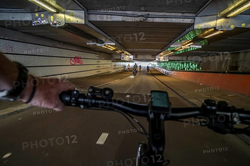 Ride your bike through the tunnel under the tracks of Utrecht Central, HBF, on the central cycle path on the Lange Viestraat, Vredenburg, in the city centre of Utrecht, lanes for pedestrians, cyclists and public transport vehicles are separated, dense cycle traffic, Netherlands