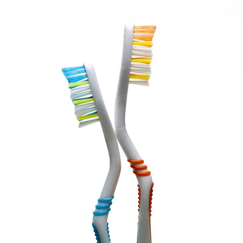 Two vibrantly colored toothbrushes stand at an angle against a plain background. They highlight the importance of dental hygiene and daily oral care routines