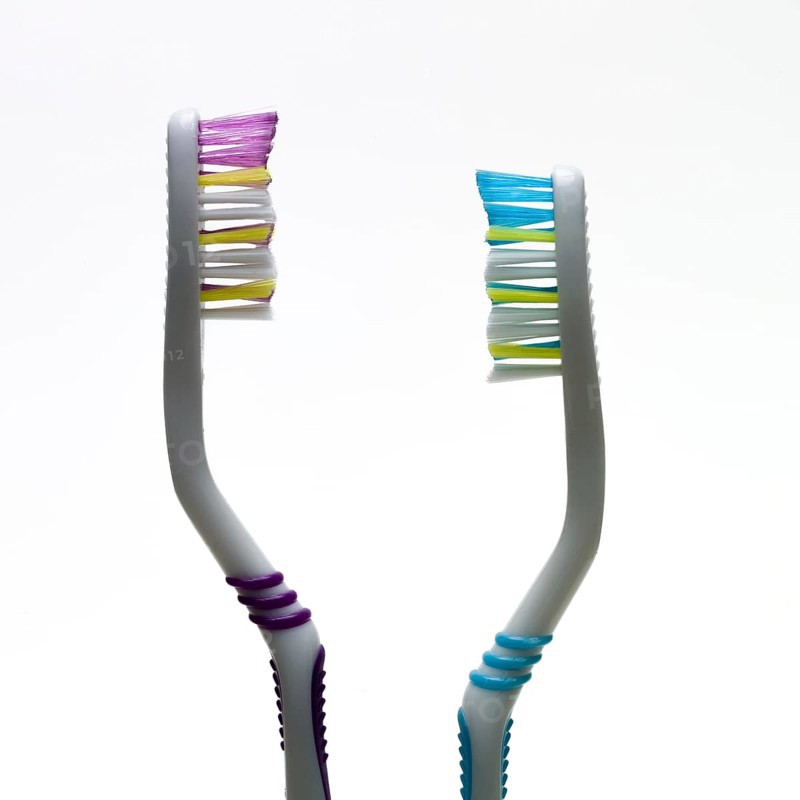 A pair of toothbrushes with bright bristles in pink and blue showcase effective hygiene tools. Their ergonomic design emphasizes comfort during daily brushing routines