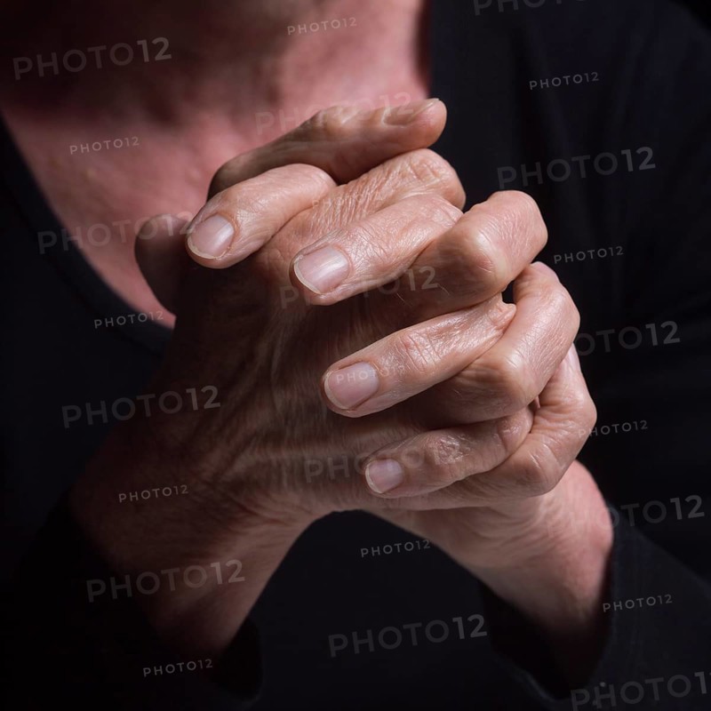 Fingers intertwined convey a sense of contemplation and tranquility. The soft lighting highlights the details of the hands, hinting at an introspective mood