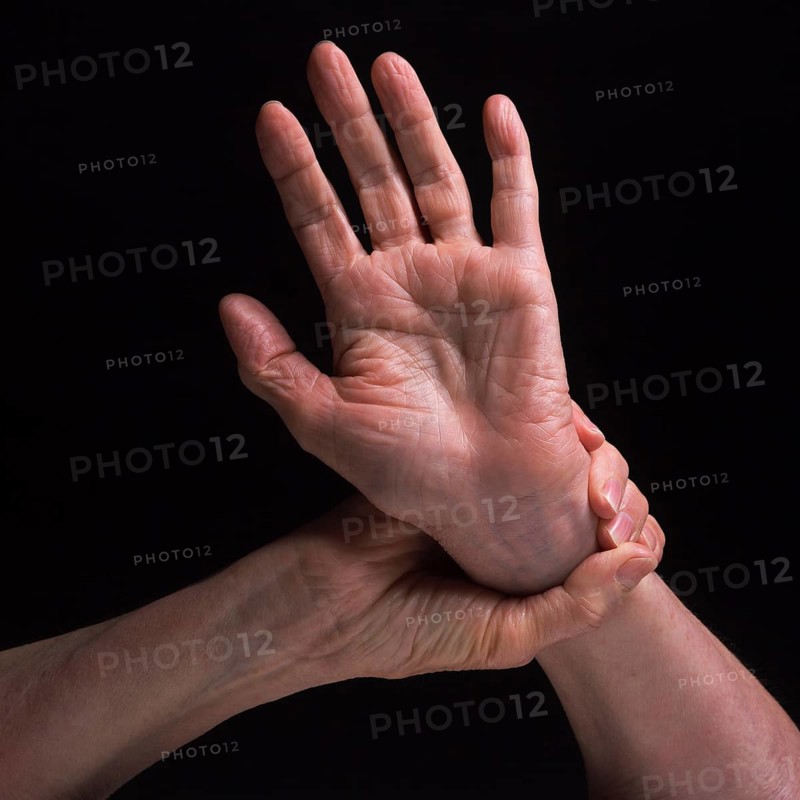 Two hands are featured in contrasting positions, highlighting the skin's texture and the grace of movement. The soft lighting enhances the details and shadows of the hands