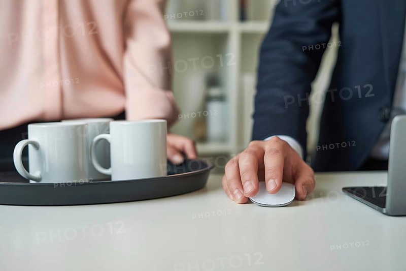 Close up of a woman's hand in pastel pink blouse holding a tray with white coffee mugs next to a man's hand on a large wireless mouse. Gender roles in the office. Generative ai, AI generated
