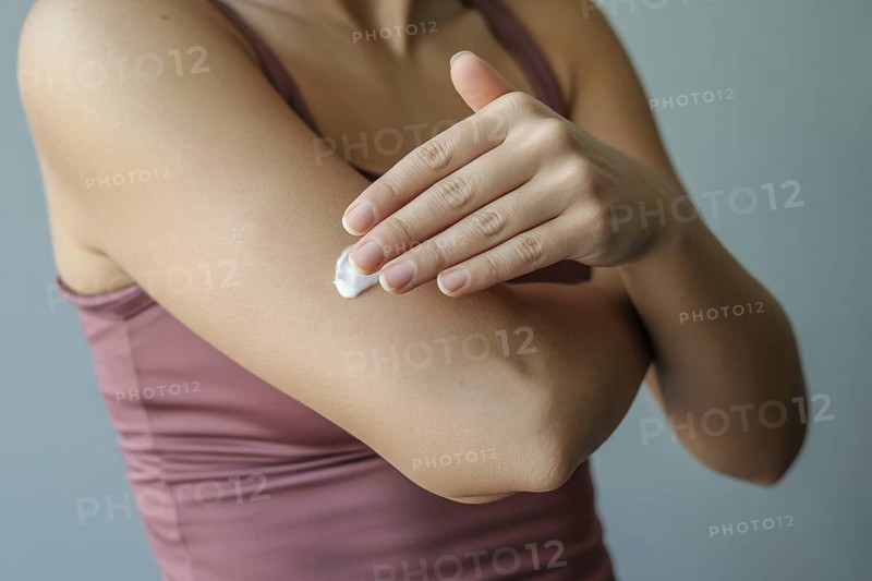 Woman applying moisturizing cream to arm. Concept for skincare and self-care routine. Generative ai, AI generated