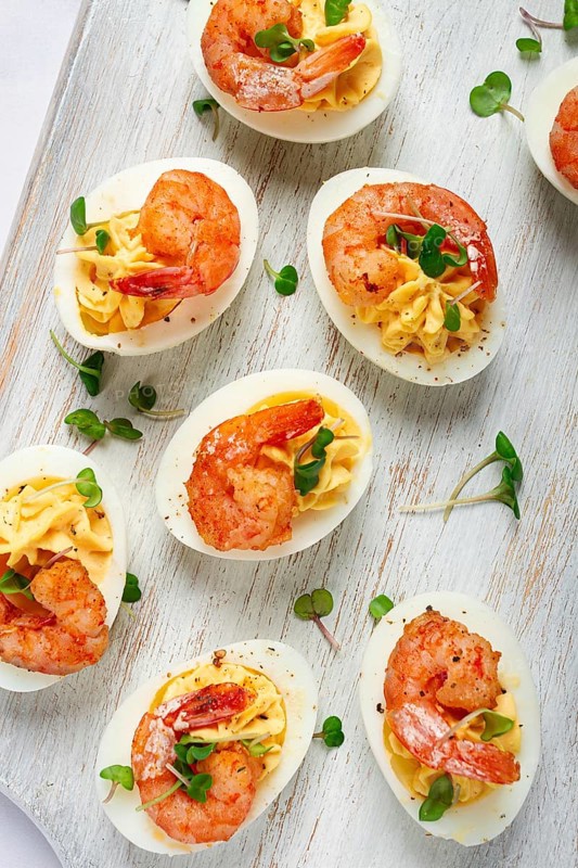 Boiled eggs stuffed with yolk and seasoned with mayonnaise, stuffed eggs with shrimp, on a white wooden chopping board, selective focus, close-up, without people