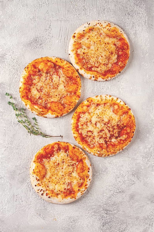 Four pizzetta Margaritas, on a light grey surface, top view