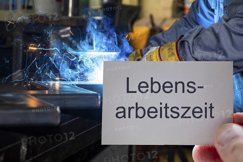 (Photomontage) Business card with the inscription LEBENSARBEITSZEIT in front of a metalworker during welding work