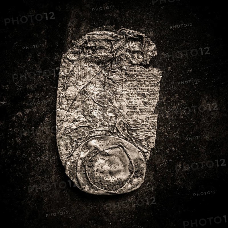 Close-up of a rusty can lying against a dark backdrop highlights the texture and wear of the metal. Signs of corrosion tell a story of abandonment in an urban setting over time