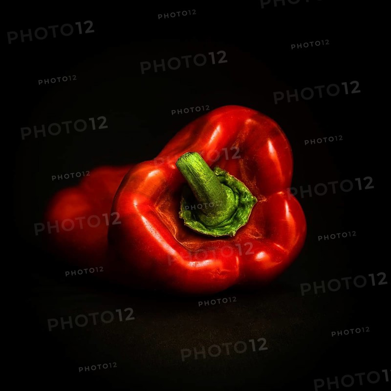 The vibrant red bell pepper, with its glossy skin, is positioned on a rich black background, highlighting its fresh, natural shape and colors