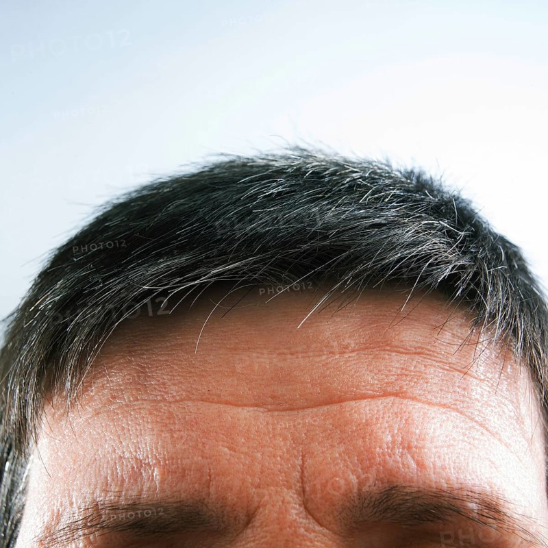 The view focuses on a man's forehead and hair, highlighting natural gray strands against a light background, creating a peaceful and calm atmosphere