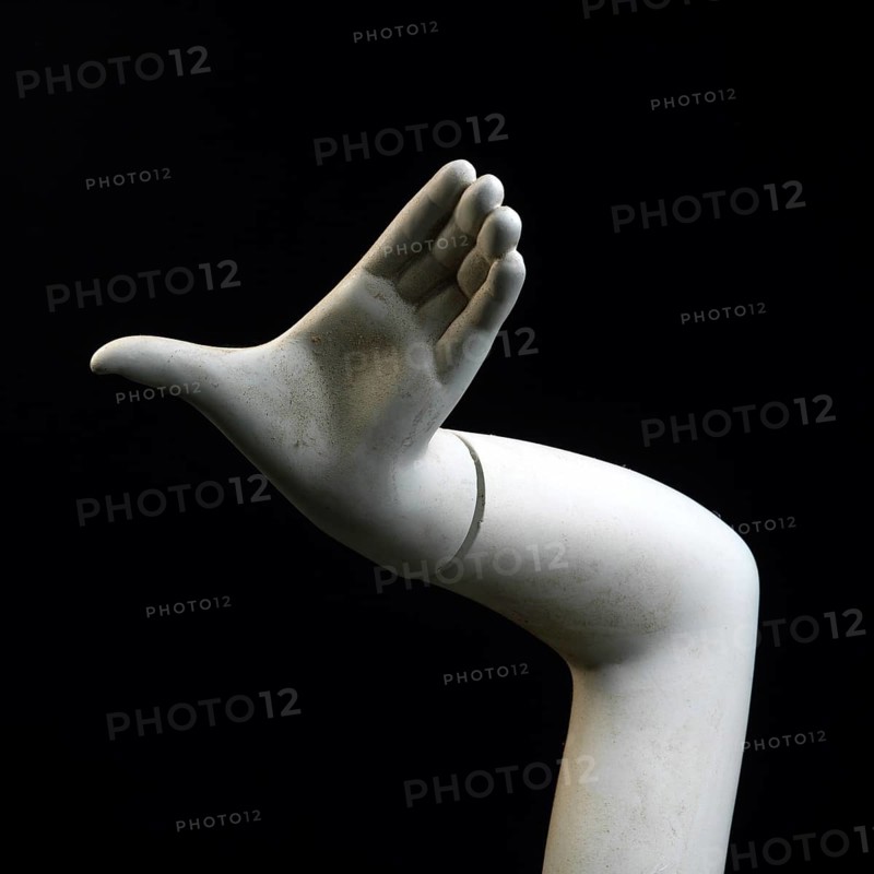 A stylized hand of a shop window dummy is elevated against a black backdrop. The sculpted hand exhibits intricate features, emphasizing form and artistic design