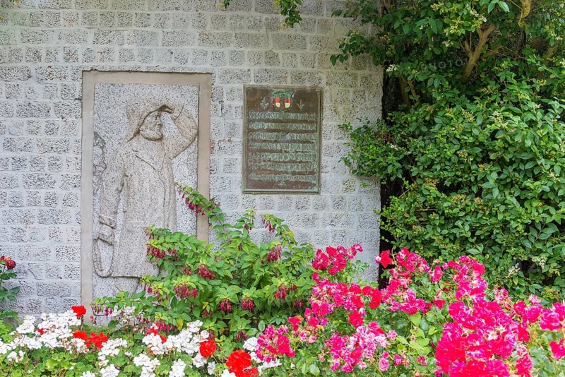 Monument, stone relief showing Jacob Andresen Siemens, founder of the seaside resort of Heligoland, fisherman, sailor with rain gear and rope, rope in hand, memorial plaque, flowery garden landscape, flower bed, spa promenade, Heligoland, Schleswig-Holstein, Germany