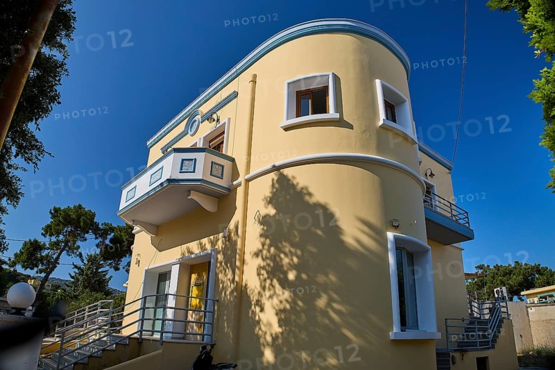 Modern yellow house with curves and balcony surrounded by trees, Armando Bernabiti, Historicism, Rationalism, Art Deco, Rationalism, Rodolfo Petraco, Fascism, Portolago, Lakki, Leros, Dodecanese, Greek Islands, Greece