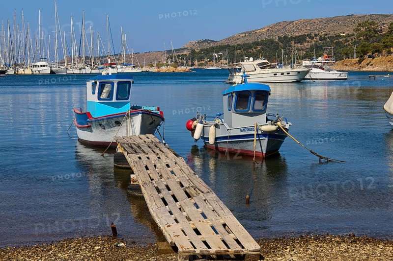 Two colourful boats on a wooden jetty with blue water and yachts in the background, Lakki, Leros, Dodecanese, Greek Islands, Greece