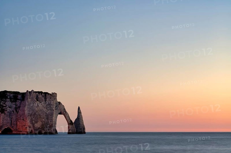 Rock arch Falaise or Porte d'Aval and rock needle Aiguille, illuminated, illuminated, Étretat, sea, steep coast, cliffs, chalk cliffs, alabaster coast, La Côte d'Albâtre, sunset, evening mood, atmospheric, Normandy, Seine-Maritime, France
